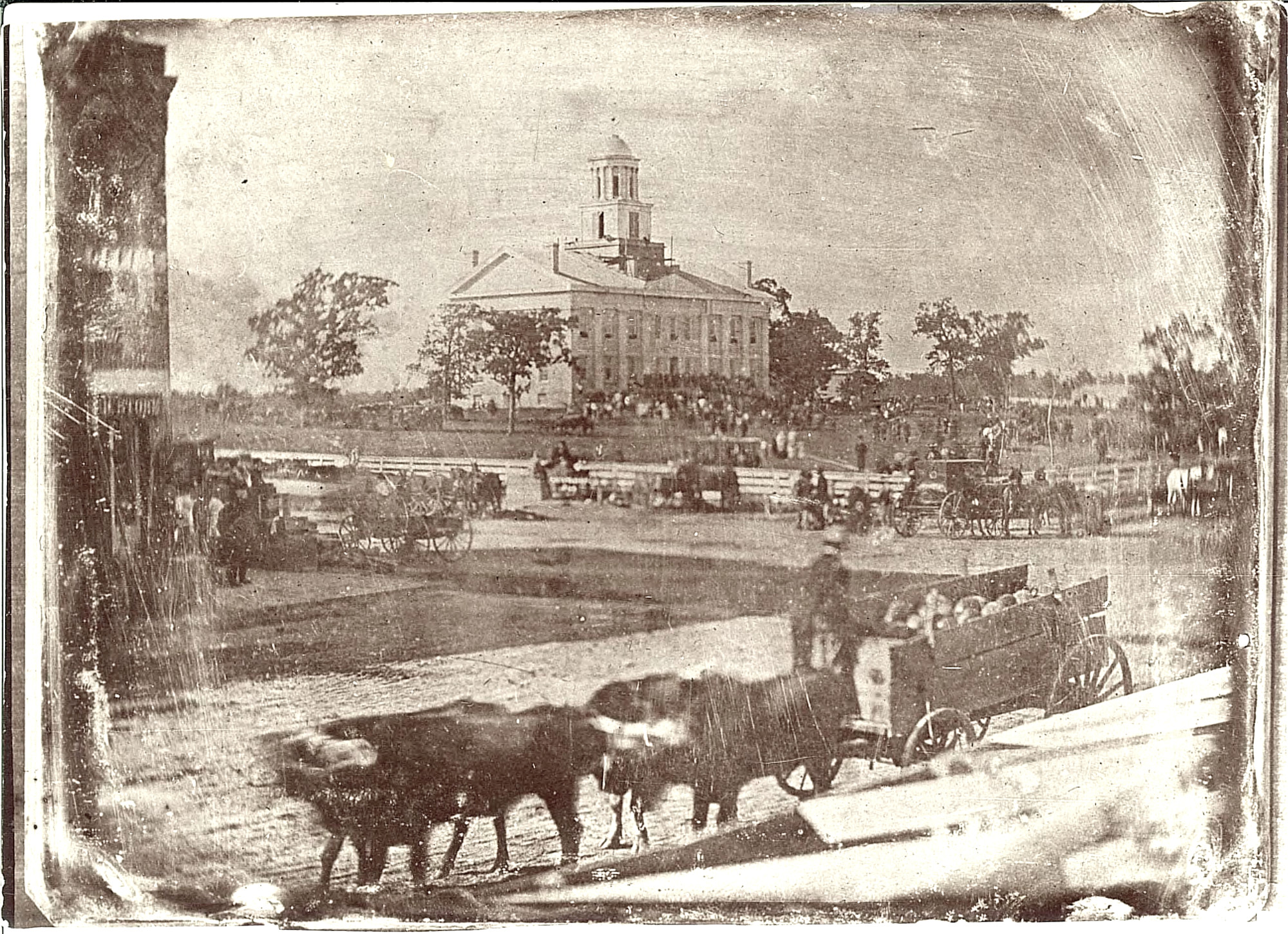 An early photo of the Old Capitol and the capitol grounds with many people attending the Johnson County Fair.